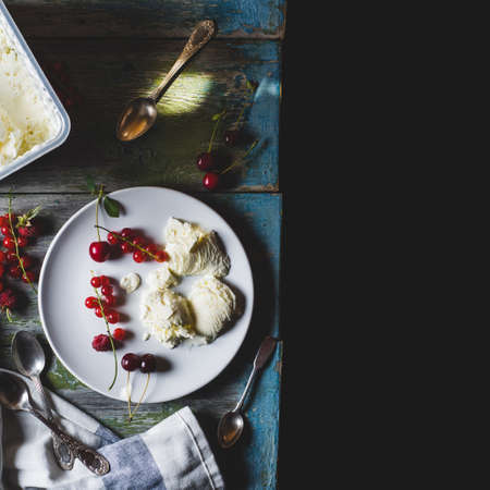 Homemade ice cream with red currants and berries on a plate over old wooden tableの写真素材