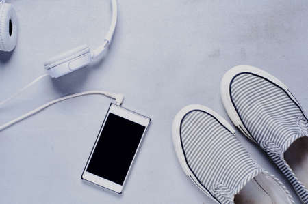 Women's striped sneakers headphones and smartphone on the grey backgroundの写真素材