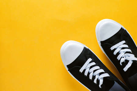 Black and white sneakers on a yellow background. Top viewの写真素材