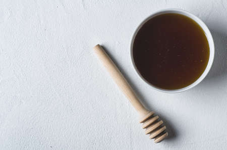 Fresh honey in a white cup on a white concrete backgroundの写真素材