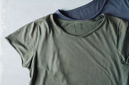 Green t-shirt on a grey concrete background. Template for designの写真素材