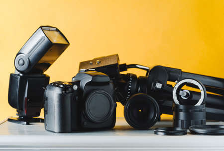 Digital camera, lenses and equipment of the photographer on a yellow backgroundの写真素材