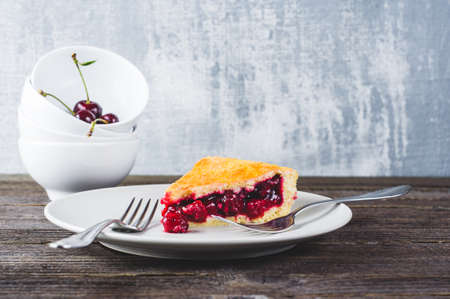 Cherry pie and fresh berries in a bowl on a dark wooden tableの写真素材