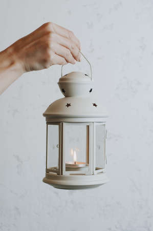 Woman holding a Christmas lantern on a white wall backgroundの写真素材