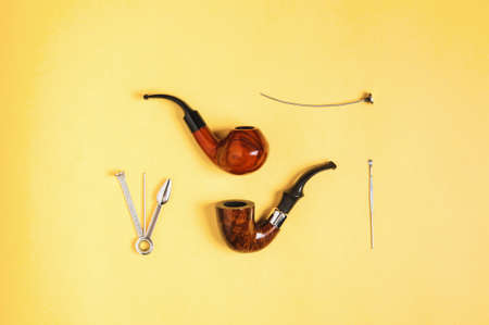 Smoking pipe and accessories on yellow background