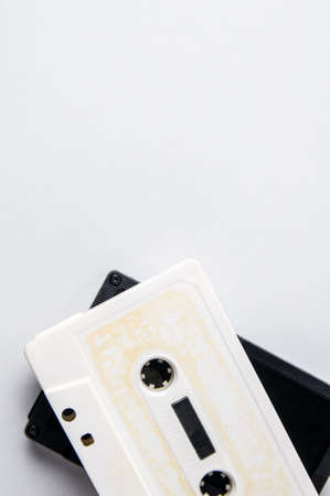 White and black audio cassettes on a light background. Place for text