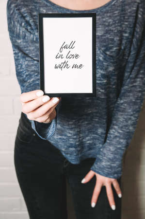 A woman holding a black frame in her hands. Template for design or textの写真素材