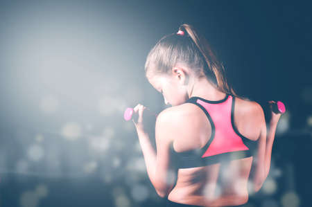 Young fitness girl with dumbbells on black background. Sport or  healthy lifestyle conceptの写真素材