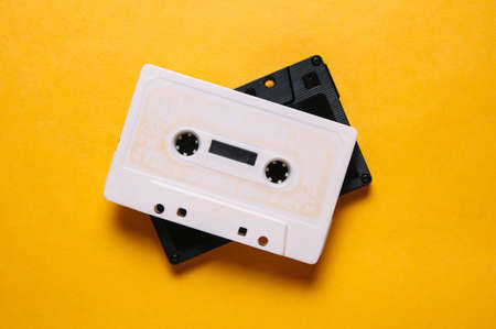 White and black audio cassette on yellow background