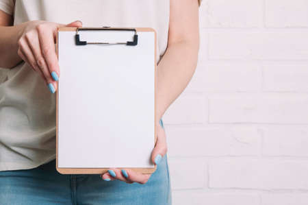 A woman holds a  clipboard in her hands. Template for text or design