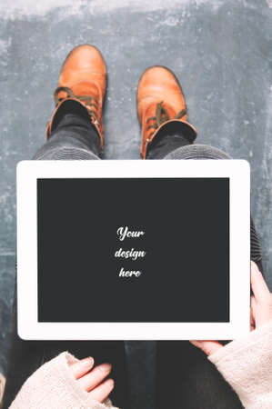 Female legs shod in Hiking boots and tablet pc. Mockup for text or appsの写真素材