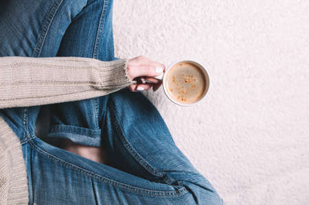 Woman holding a Cup of coffee in her hands. Top view