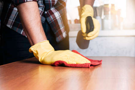 The man in yellow gloves wash the table. The concept of cleaning