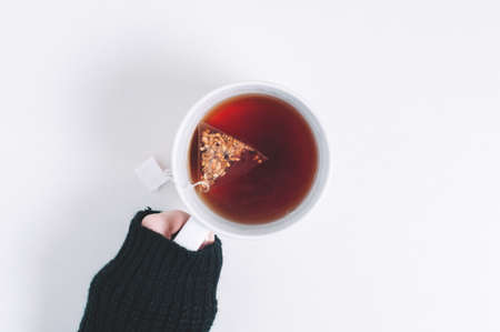 Woman holding a cup of tea in her hands. Top view and white backgroundの写真素材