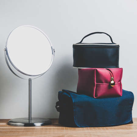 Cosmetic mirror and cosmetic bags on a pale backgroundの写真素材