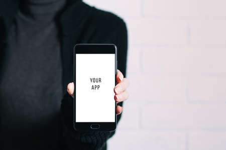 A woman holding a smartphone in her hands. Template for design or app
