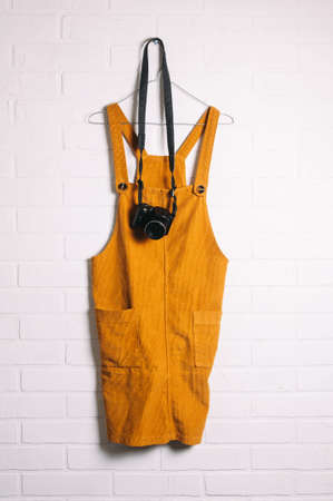 Yellow velvet dress and camera in front of a white brick wallの写真素材