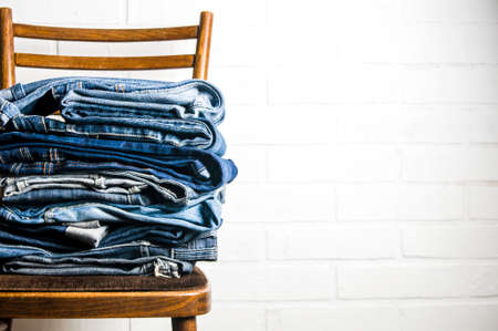 A stack of old jeans on a light backgroundの写真素材