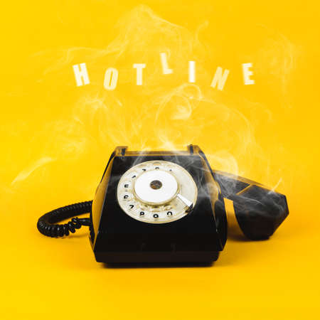 Old phone and text Hotline on yellow background