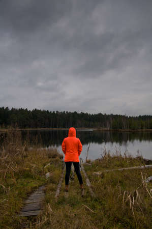 Girl tourist in an orange jacket on background of autumn nature