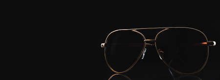 Gold-rimmed sunglasses on a dark background. Space for text or designの写真素材