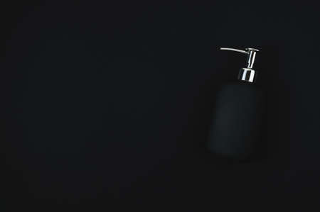 Black liquid soap bottle on a black backgroundの写真素材
