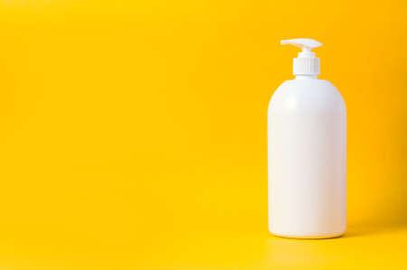 White bottle for cleaner or liquid soap on yellow background. Mock up for text or designの写真素材