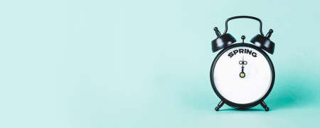 Vintage alarm clock and text "Spring" on it on turquoise backgroundの写真素材