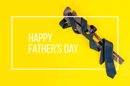 Fathers day concept. A rusty wrench and a black tie on a bright yellow backgroundの写真素材