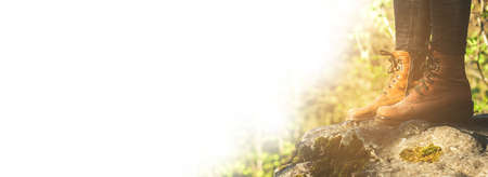 Female legs shod in Hiking boots on the forest background. Copy spase for text or designの写真素材