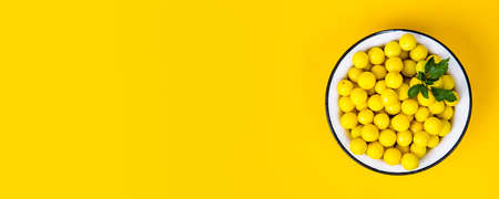 Yellow plums in white plate on yellow backgroundの写真素材