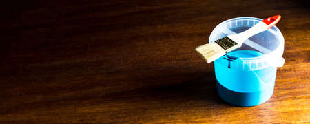 A can of blue paint and a brush on a wooden table. Space for text or designの写真素材