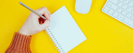 The hand of a left-handed woman holds a pencil in her hand. International concept for a left-handed...
