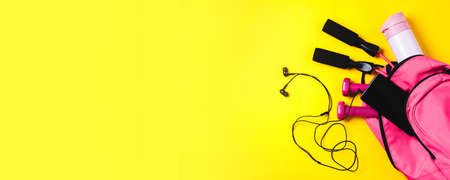 Pink sports bag and accessories on yellow background