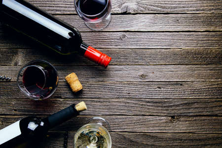 Glasses of red and white wine and bottles on a dark wooden background. Flat lay and top view, copy space for text or designの写真素材