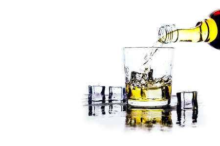 Whiskey pours from a bottle into a glass on a light backgroundの写真素材