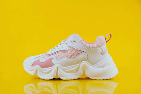 White and pink sports sneakers on an yellow backgroundの写真素材
