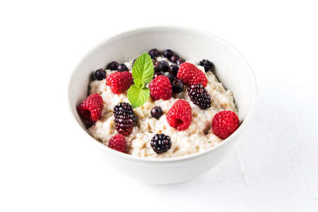Oatmeal porridge with raspberries and blackberries in a light plateの写真素材