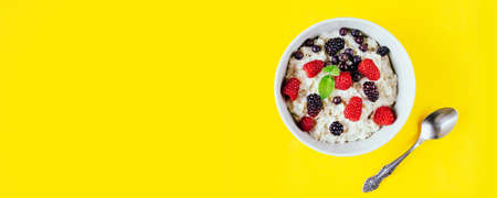 Oatmeal porridge with raspberries and blackberries in a light plateの写真素材