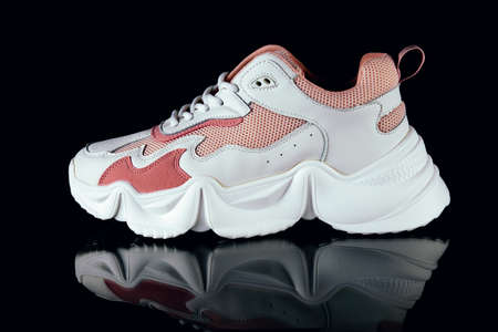 White and pink sports sneakers on an black backgroundの写真素材