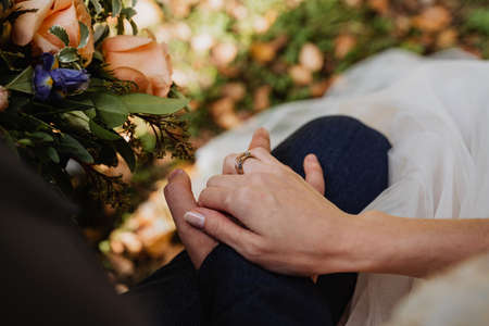 a man and a woman hold each other's hand, wedding ring on the finger, newlyweds together, wedding moment, relationshipの写真素材