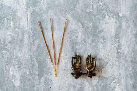 metal door handles in the shape of hands folded in mudra, shot on a textured gray background, close-up, separate object, yoga theme, bronze hue, Indian motif, incenseの写真素材