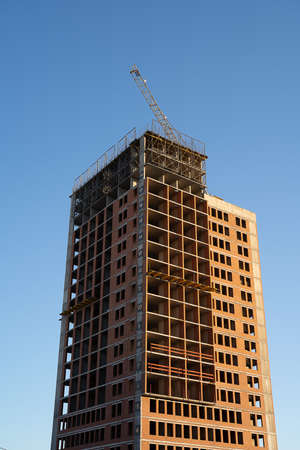 construction of a high-rise building against the blue sky, multi-storey building, red brick house