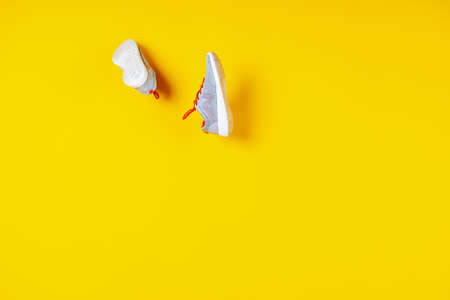 sneakers flying in the air on a yellow background, concept photoの写真素材