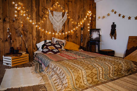 loft room on the second floor in a wooden style with lights, warm colors, interior design, bed on the floor, a cozy place to sleepの写真素材