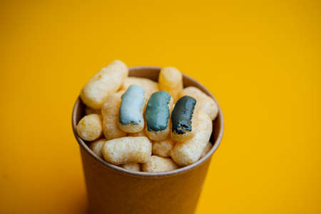 yellow corn sticks in a glass on a colored background, a full box of sweet corn sticks, a treat for children, yellow background, minimalismの写真素材