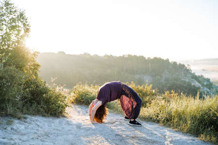 young girl doing yoga in nature, stand on the bridge, outdoor fitness classes, asanaの写真素材