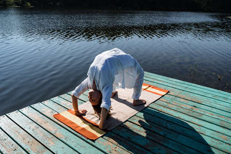 a young girl does yoga on a lake on a Sunny summer day, meditation, relaxing pose, solitude in nature, peace, relaxation, asana, healthy lifestyle, life style, Zenの写真素材