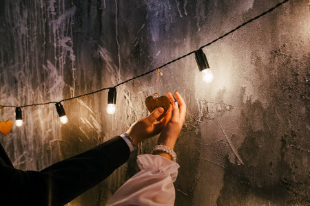 wooden heart with the inscription love in the hands of a man and a woman, evening of romance, light of love between two peopleの写真素材