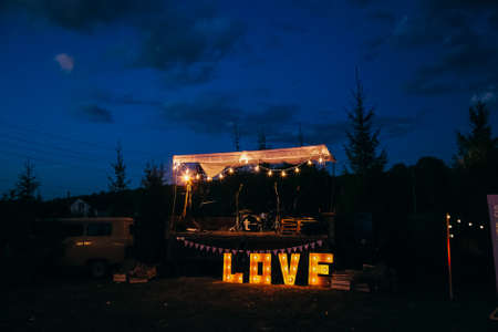 Big letters love with light bulbs. Festive decoration of a celebration in nature. The word love glows in the dark.の写真素材